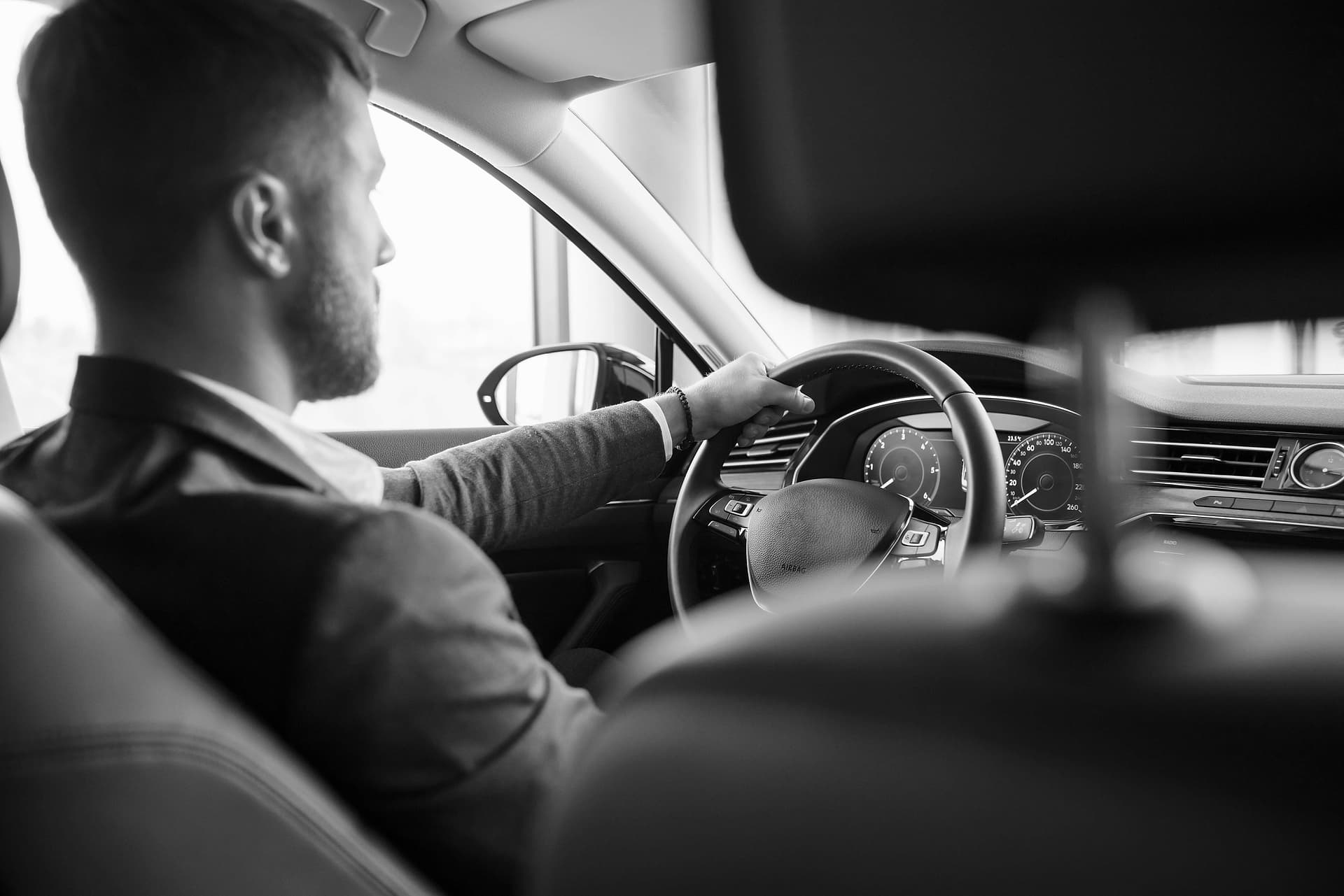 Motorista executivo de terno ao volante, visto do banco traseiro